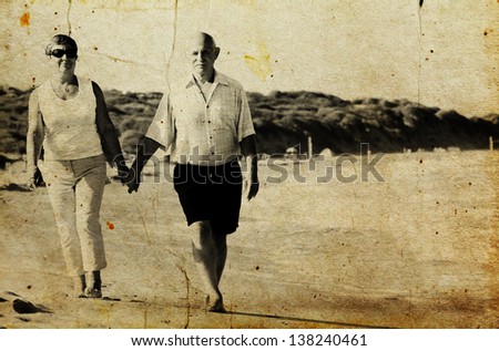 Happy senior couple walking together on a beach. Photo in old image style.