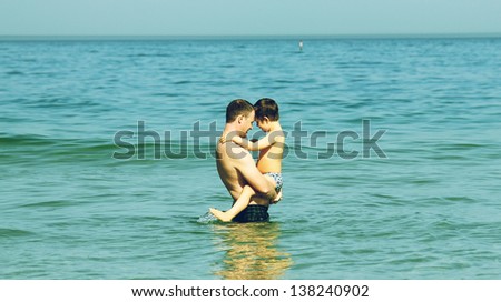 father and son swimming in the sea. Photo in old image style.  Touching relations of the father and the boy with the syndrome of autism.