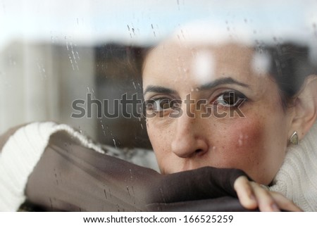 Art portrait of a beautiful young sadly girl looking through the window