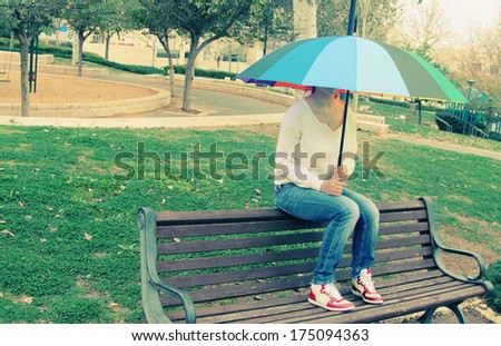 Young woman sitting under a big rainbow umbrella