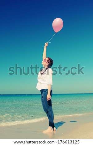 Young redhead woman holding pink balloon