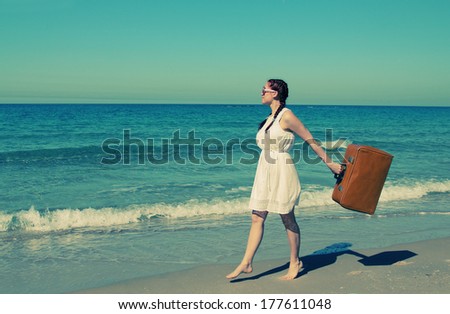 woman with suitcase on the beach. Photo in old image style.
