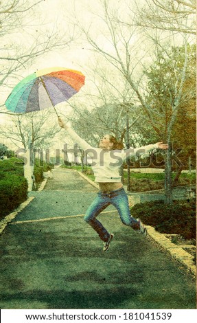 Young woman jumpimg with big rainbow umbrella. Photo in old image style