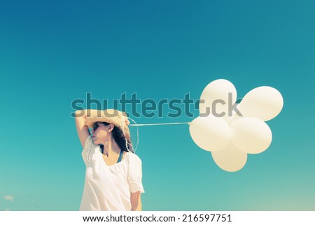 woman with white balloons on seaside