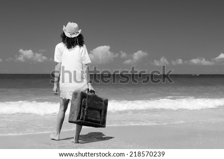 woman with suitcase on the beach