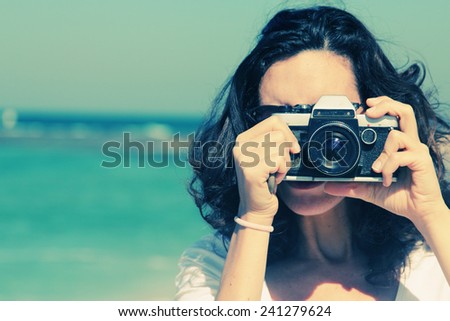 Woman with vintage retro camera having fun on the beach on blue sea background