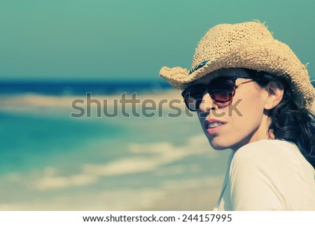 Beautiful girl smiling on the beach with the sand, sea and blue sky in the background