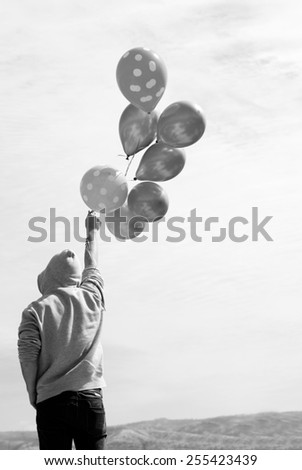 Man holding colorful balloons outside