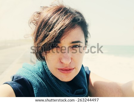 Beautiful woman smiling on the beach with the sand, sea and blue sky in the background. Selfie.