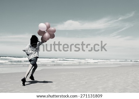 beautiful woman holding red balloons and walking on seaside