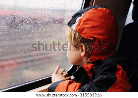 7 years old boy sitting in the train and looking to the rain