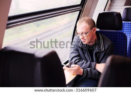 Handsome 40 years old man holding smartphone and traveling in the train