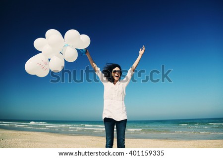 woman holding white balloons on seaside