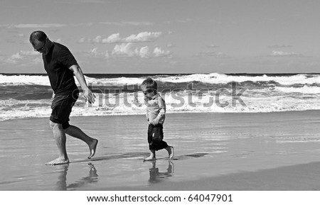Black and white photo. Father playing with his son at beach