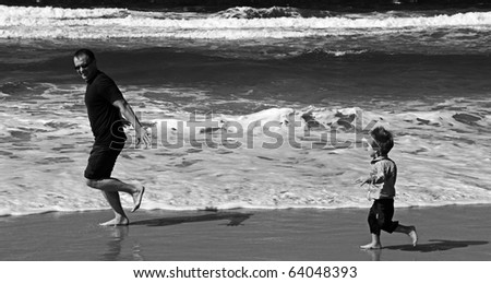 Dad and son playing on the sea. Autumn sea, strong waves, sharp colors. Black and white photo