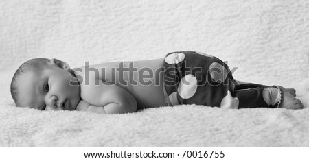 newborn girl in shorts lying on white blanket