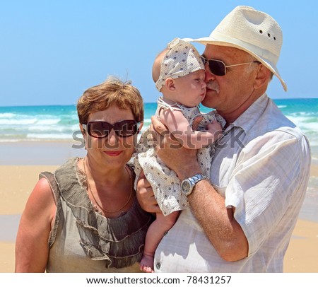 happy grandpa and grandma are holding a little granddaughter. Background - the sea