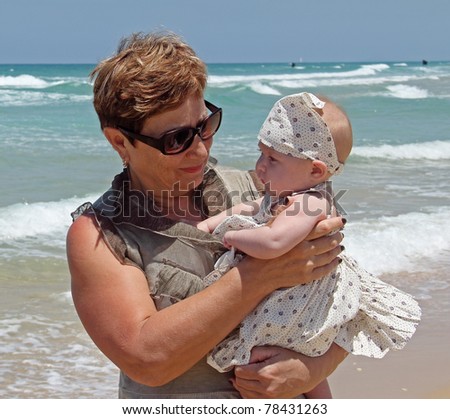 happy grandma is holding a little granddaughter. Background - the sea