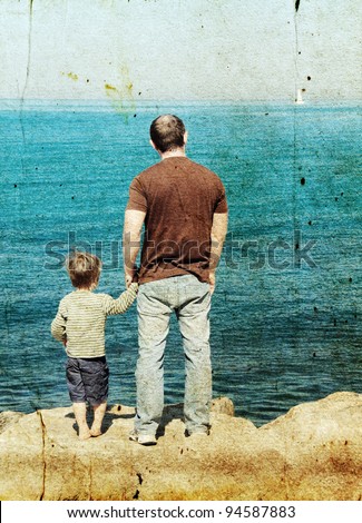 Father and son looking at a white sail in the sea. Photo in old image style.