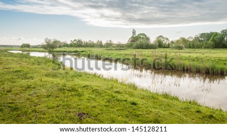 Rural landscape in the Netherlands with a narrow river meandering through the landscape.