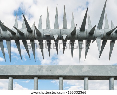 Detail of a zinc plated steel fence with sharp spikes.