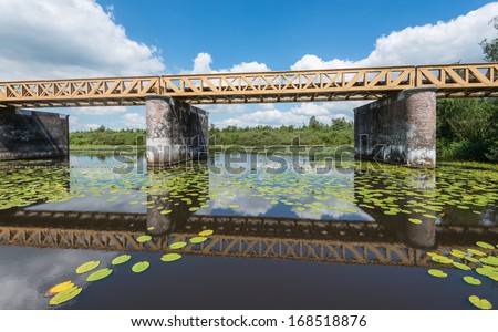 Old railway bridge reflected in the mirror smooth water surface.