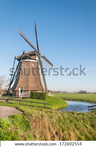 Typical Dutch polder landscape with two windmills in the green polder area and the edge of a small village in the background.
