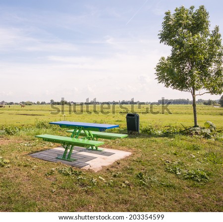 Green and blue plastic picnic table and benches in a rural area in the Netherlands.