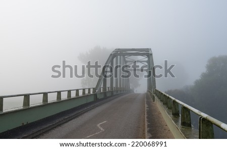 An old steel arch bridge on a foggy morning in early autumn season.