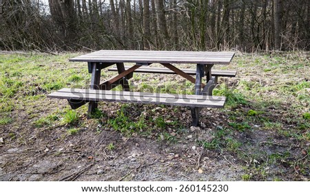 Wooden picnic bench and table on the edge of a forest in the end of the winter period.