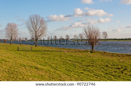 Floodplains with bare trees and a river with ships in the Netherlands
