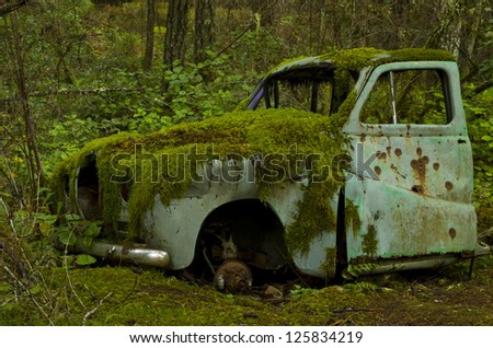 Abandoned old car covered in moss in the forest