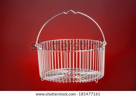 Stainless steel kitchen basket for vegetables on a red background