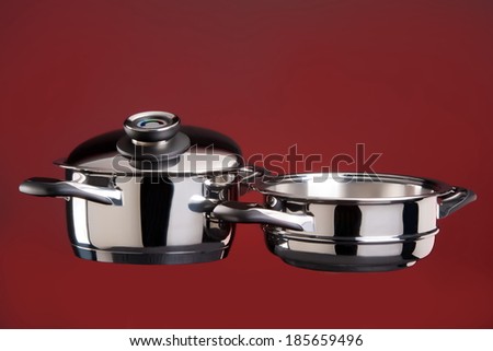 Set of stainless steel cookware on a red background