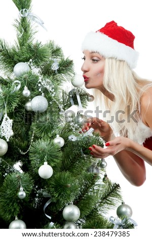 Beautiful sexy blonde girl in a Christmas costume at a Christmas tree on a white background isolated