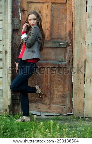 Beautiful sexy brunette girl in a red blouse posing in old wooden door