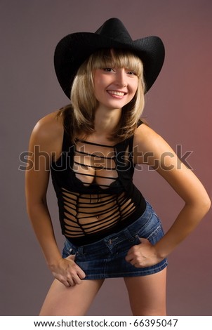 Portrait of the beautiful sexual girl of the blonde in stetson pose in studio on pink background
