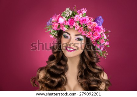 Studio portrait of a beautiful woman with flowers rose in her hair. Flower girl.