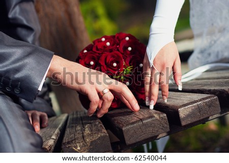 Hand of  groom and  bride with  rings near wedding bouquet