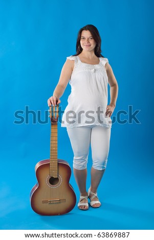 Pregnant woman with the guitar, isolated on blue