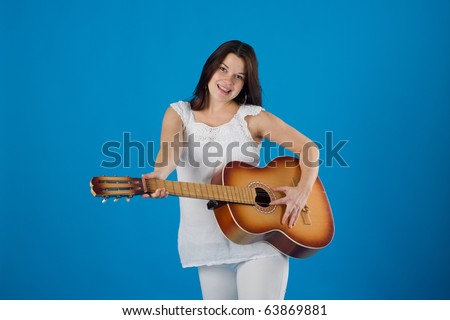 Pregnant woman with the guitar, isolated on blue
