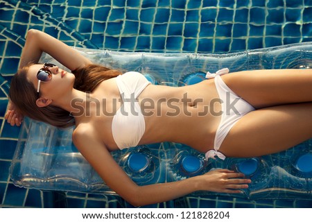 Beautiful woman sunbathing in swimming pool