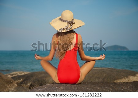 Rear view of sexy woman in red bikini and hat. Meditation and relaxing concept