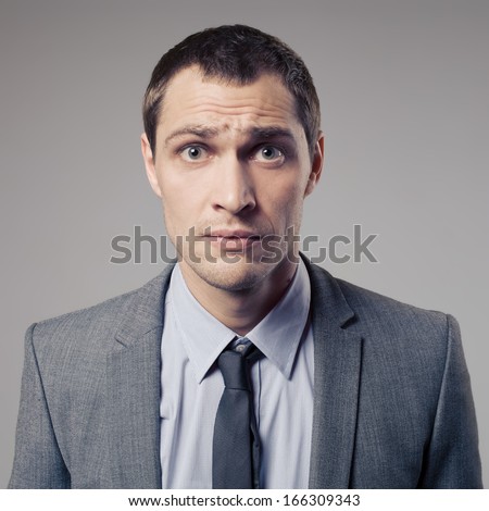 Confused Businessman On Gray Background