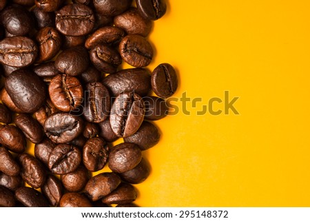 Roasted coffee beans close up. Yellow background. Space for text.
