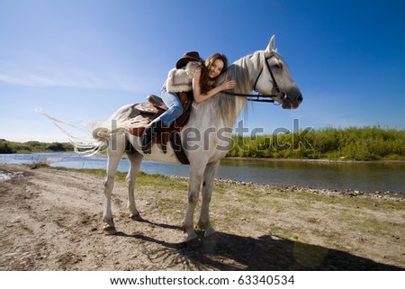 young cowgirl on white horse at the rural river