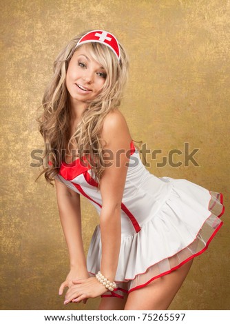sexy blonde woman in seductive nurse costume on golden background
