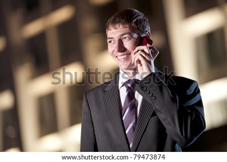 happy businessman talking on cell phone at night city in the background
