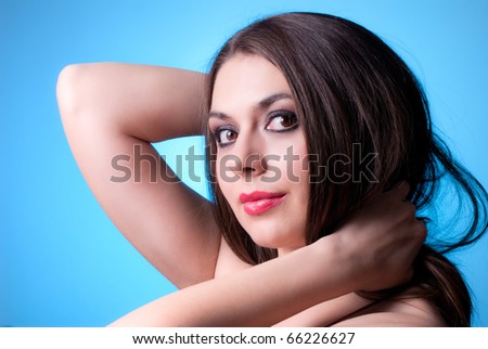 Beautiful brunette with shinny red lips twist a hair on blue background