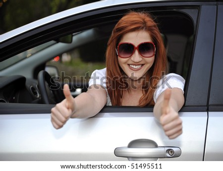 Woman in sunglasses smiling from her car to camera